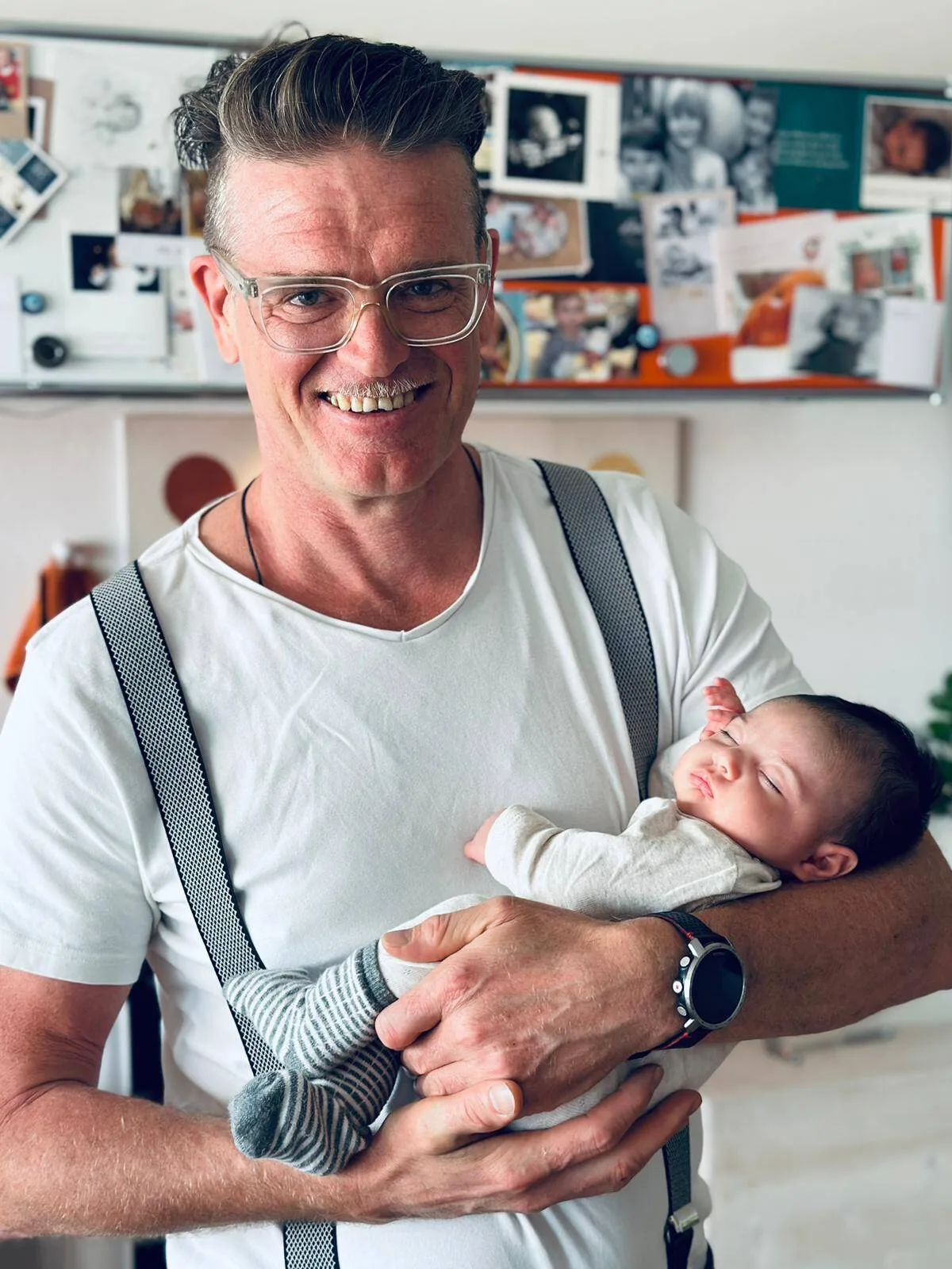 Male doctor holding a sleeping newborn baby, powerfully illustrating the practice's obstetrics and holistic family-care approach.