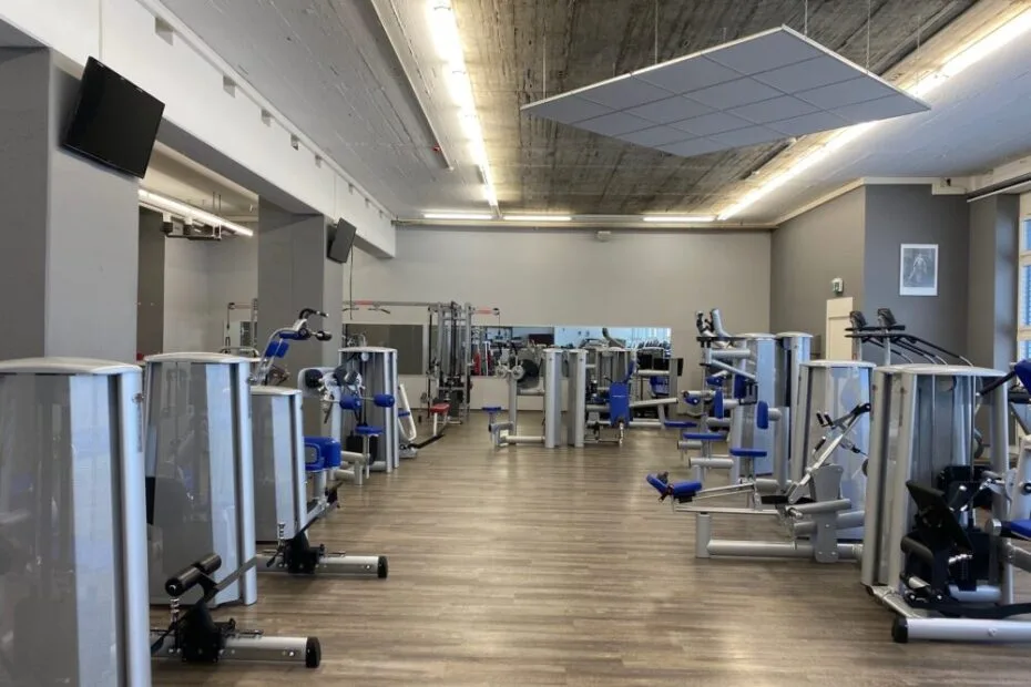 A well-equipped, quiet gym room with blue-and-silver strength machines on a wooden floor.