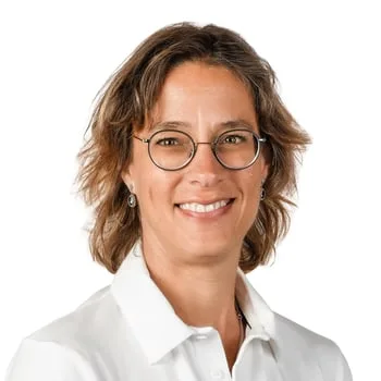 Close-up square portrait of therapist wearing glasses and white shirt, showing genuine smile and professional demeanor that builds patient confidence.