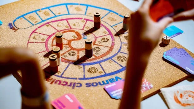 Eine fröhliche Familie spielt gemeinsam ein Brettspiel am Wohnzimmertisch, lacht und interagiert eng, während sie aufeinander konzentriert sind, ohne digitale Ablenkungen.