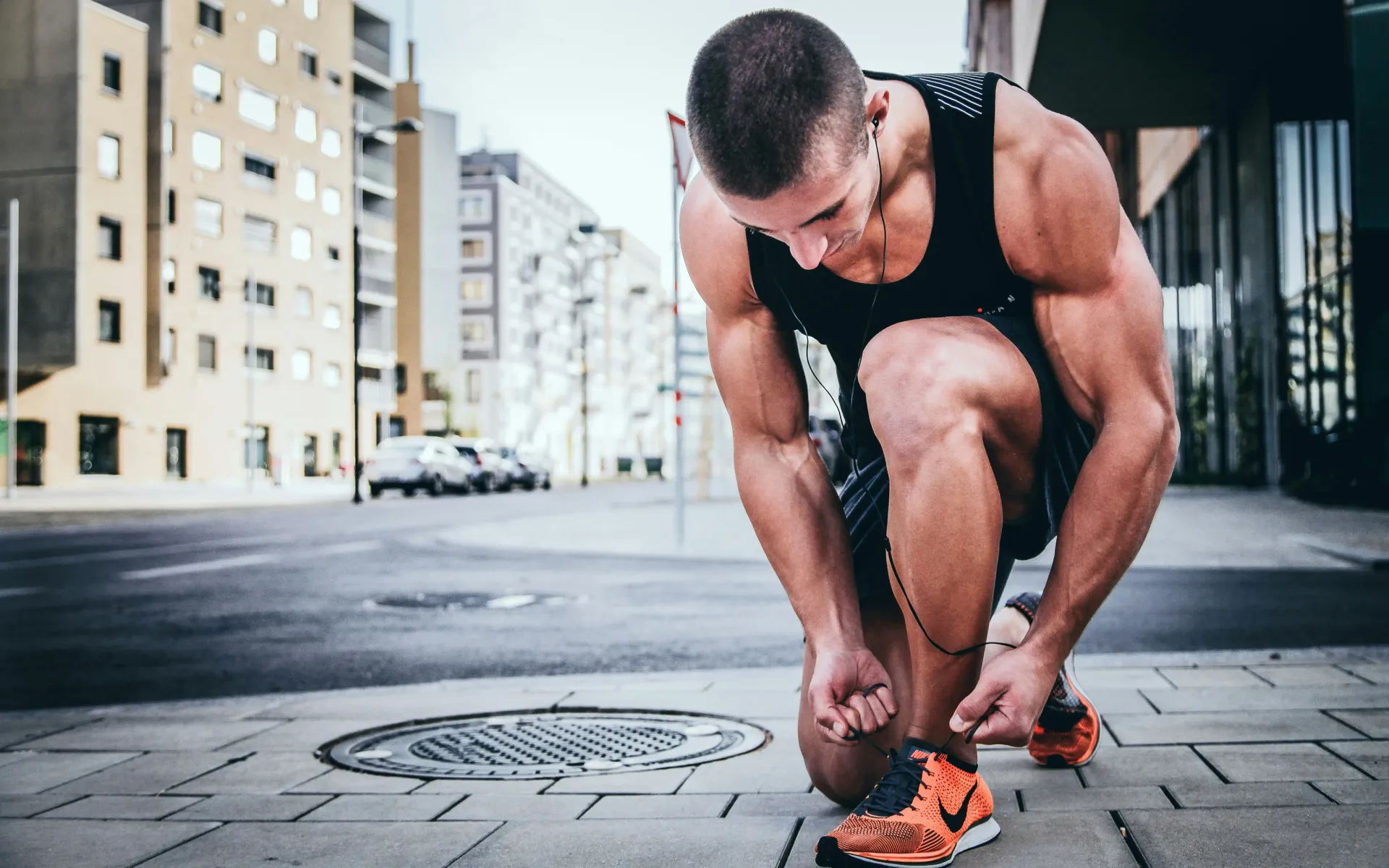 Athlete tying running shoes on urban street, capturing the personal moment of preparation and focus central to individual coaching practice.