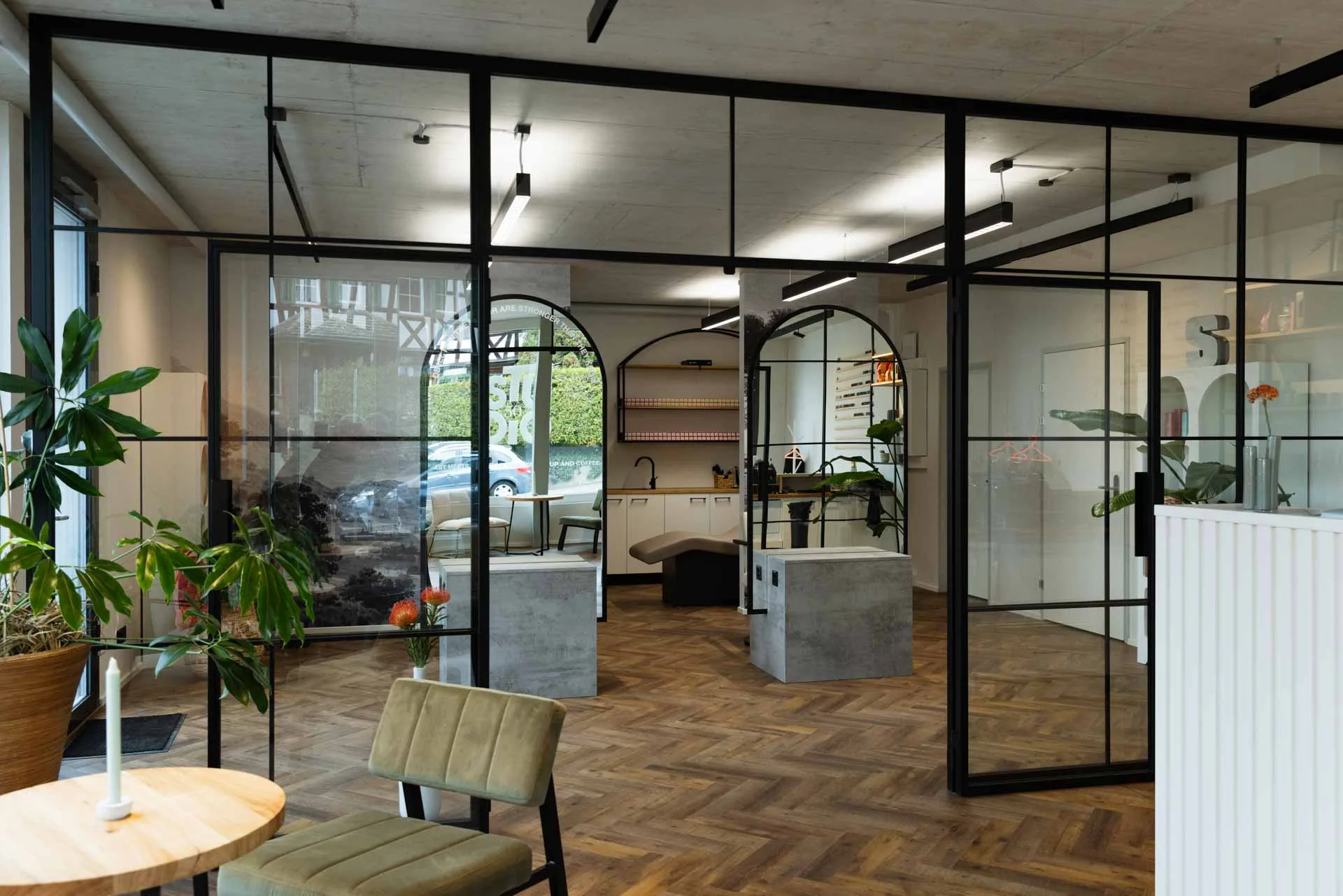 Bright, welcoming studio interior with herringbone floors, plants, and cozy seating — perfectly captures the warm, gallery-like atmosphere described in the article.