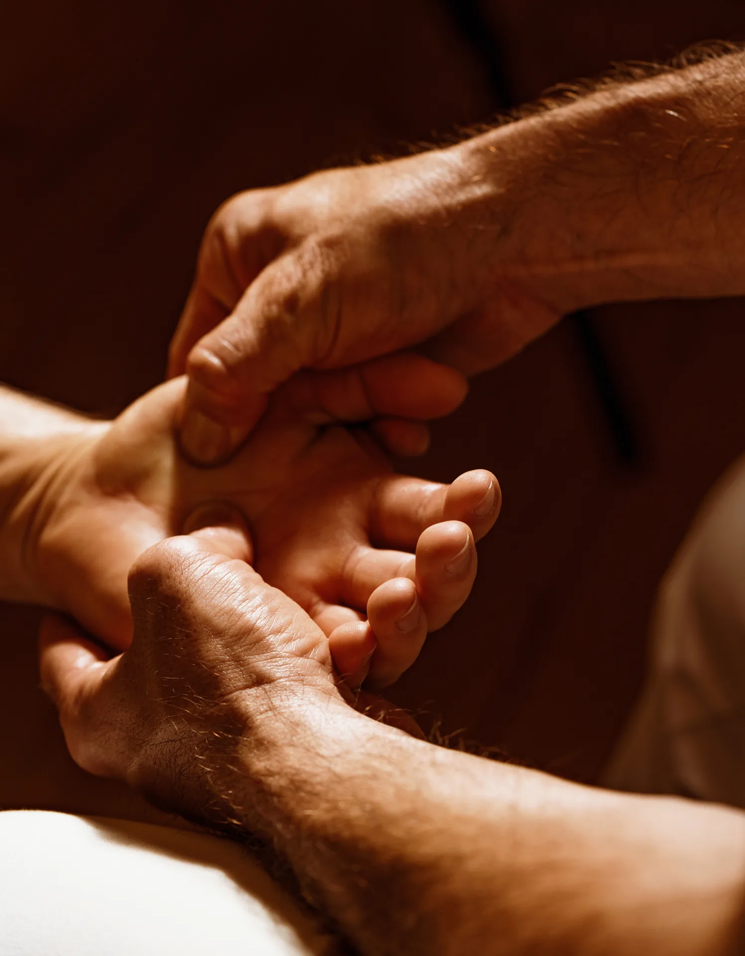 Therapist using both hands to work along the muscle beside the spine with focused pressure.