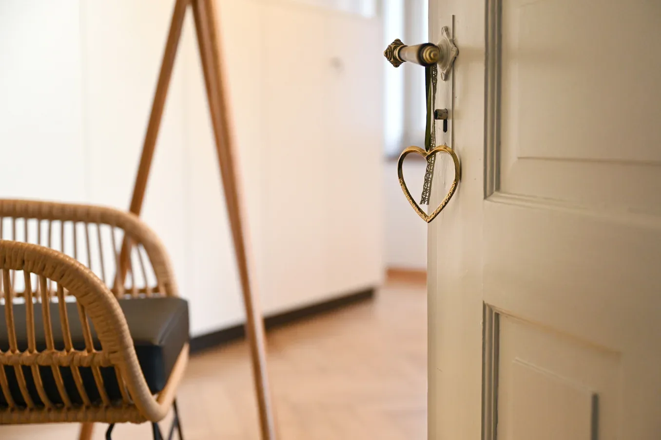 A bright consultation room with a wooden table, rattan chairs, and a heart on the door.