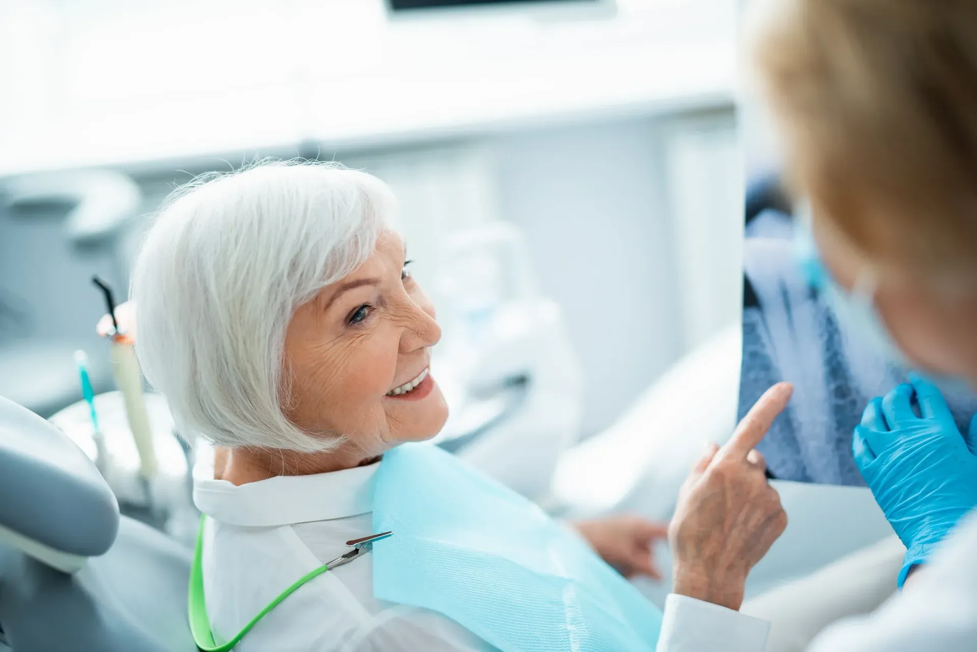 A dentist examines a female patient's teeth using dental instruments during a checkup.