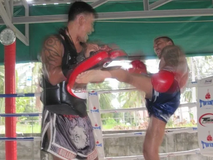 Oliver Alessandri raises a young fighter's gloved hand in victory inside a boxing ring.
