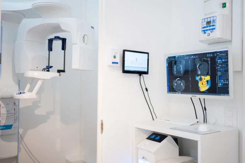 Modern CBCT 3D imaging machine beside a monitor showing skull scans, representing cutting-edge technology in holistic dentistry.