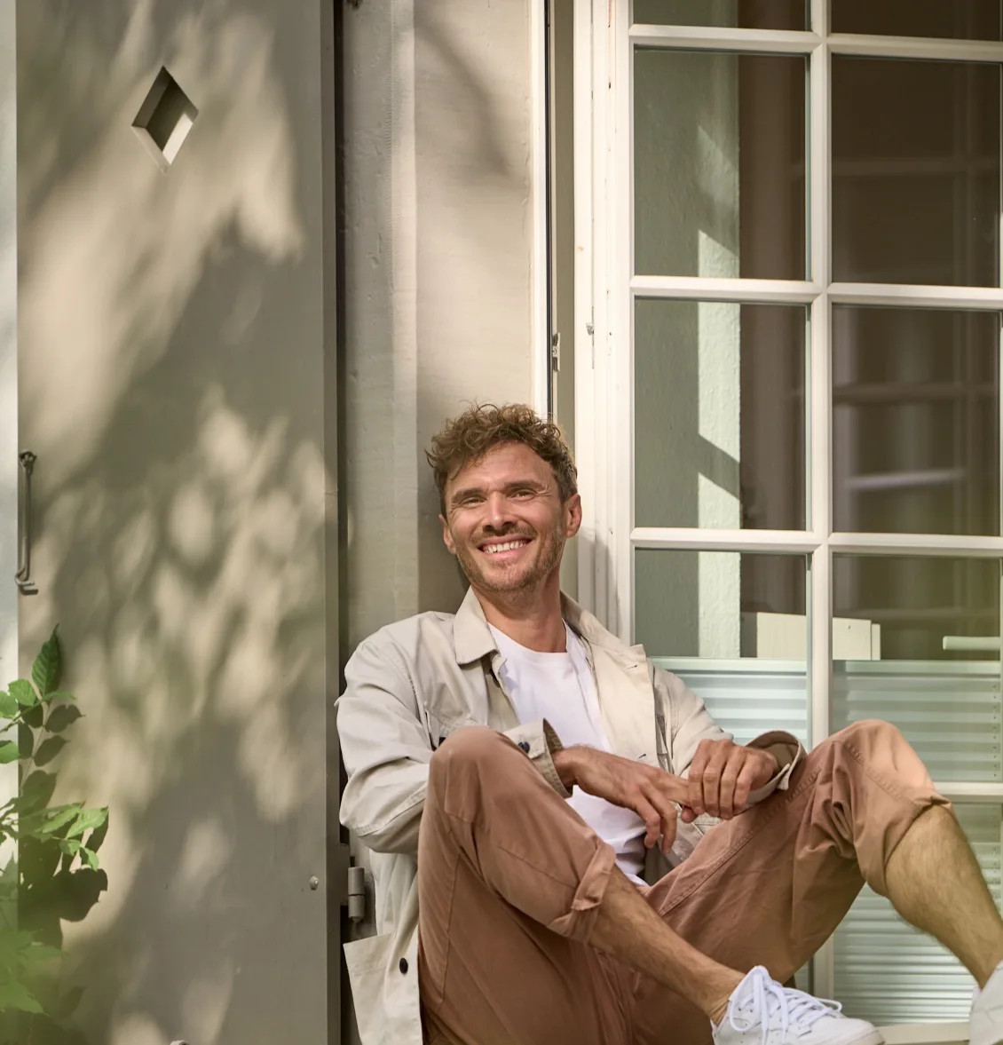 Man relaxing in doorway with natural light, embodying calm presence and self-awareness central to body-centered healing.