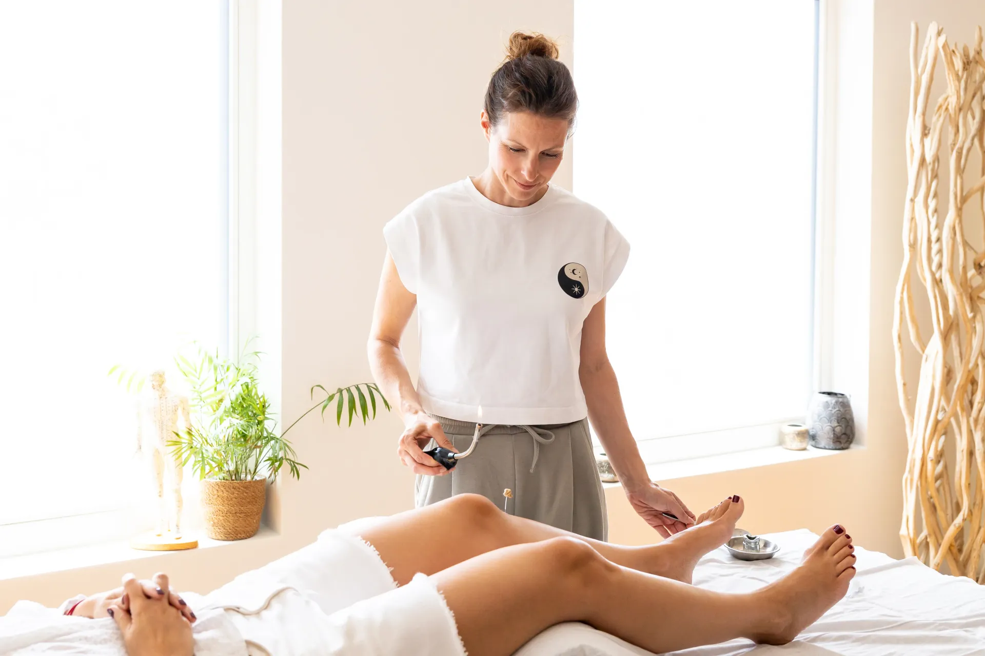 Therapist performing moxibustion acupuncture treatment on a patient's foot and ankle.