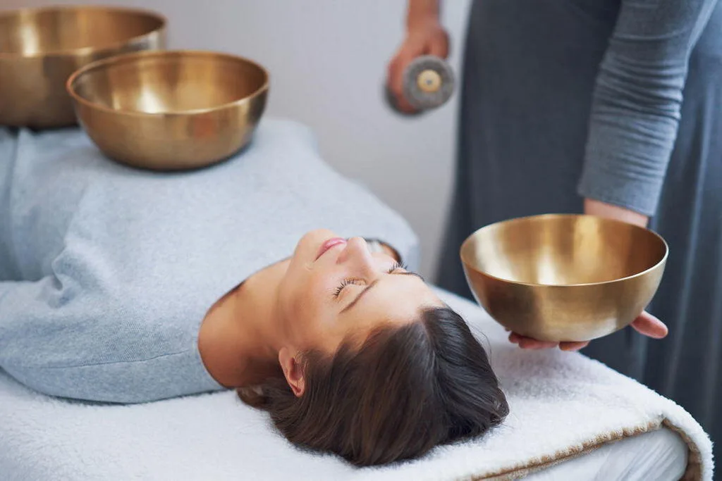 A woman receiving a relaxing head massage on a treatment table, perfectly illustrating the hands-on therapeutic care offered at bewusstgsund.