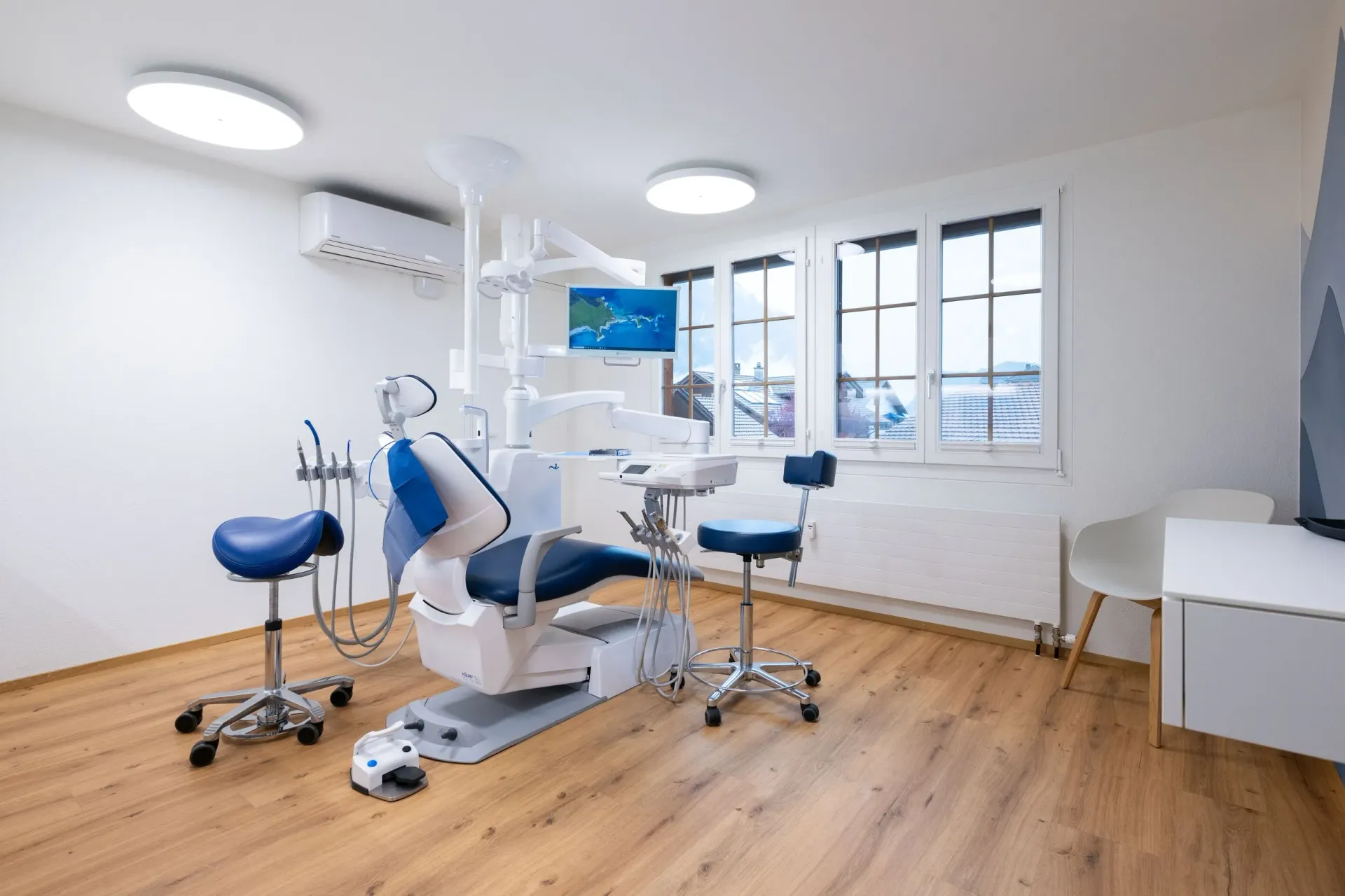 Smiling male dentist in navy scrubs poses confidently in a bright modern clinic setting.