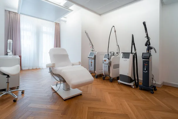 Treatment room with laser and aesthetic medical devices alongside white reclining chair.