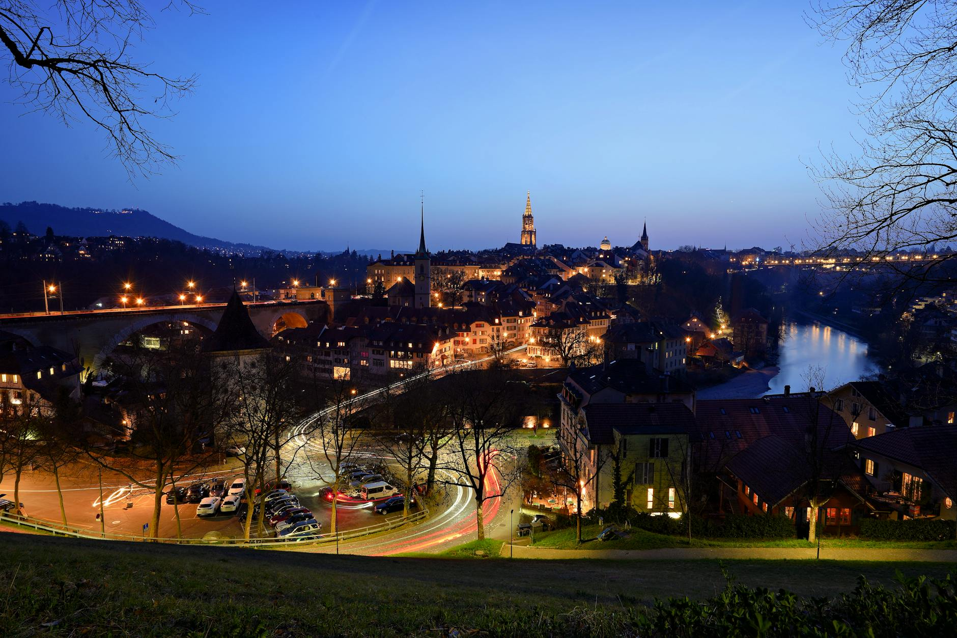Eine entspannte Person im Bett in einem ruhigen, pflanzenreichen Schlafzimmer mit Schweizer Landschaftsbildern an der Wand, die erholsamen Schlaf symbolisiert.