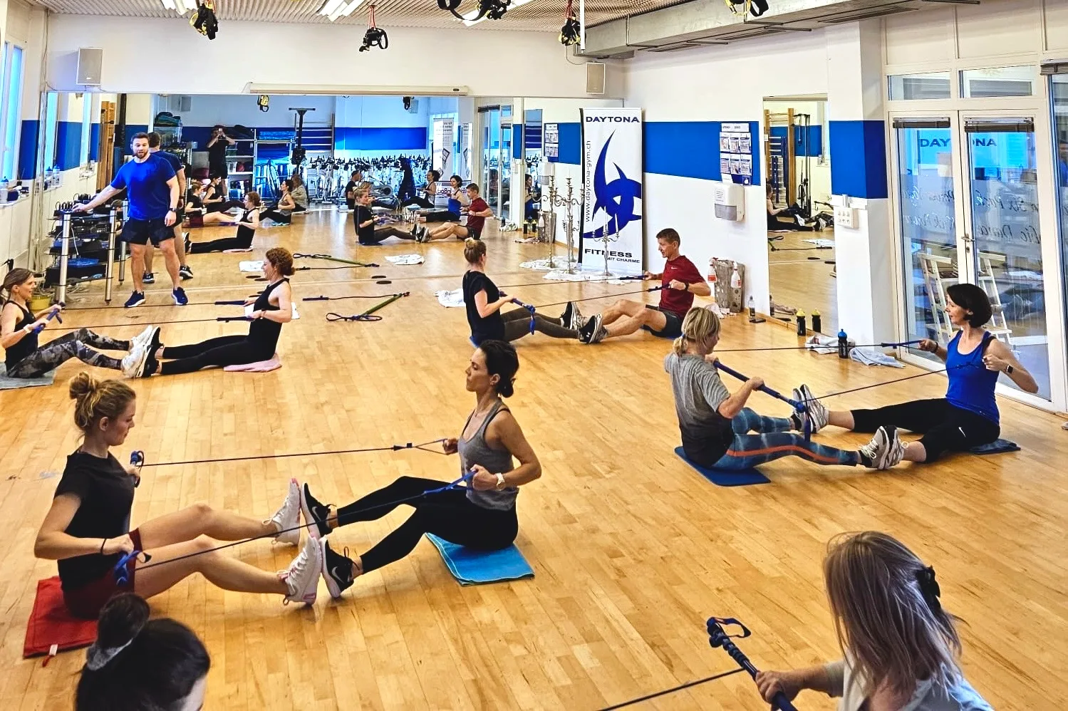 A smiling Daytona trainer crouches with a client during a movement assessment, perfectly embodying the personal, human-centered coaching philosophy of the center.