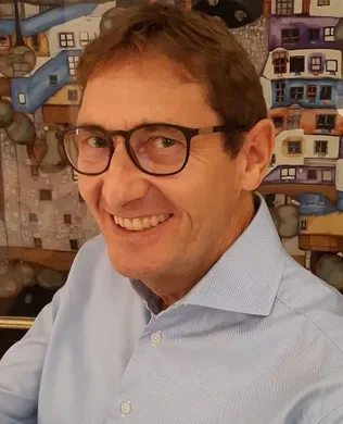 Portrait of Urs-P. Reber, the dental prosthetist behind the Bülach practice, smiling warmly — perfectly embodying the trust and personal care the article describes.