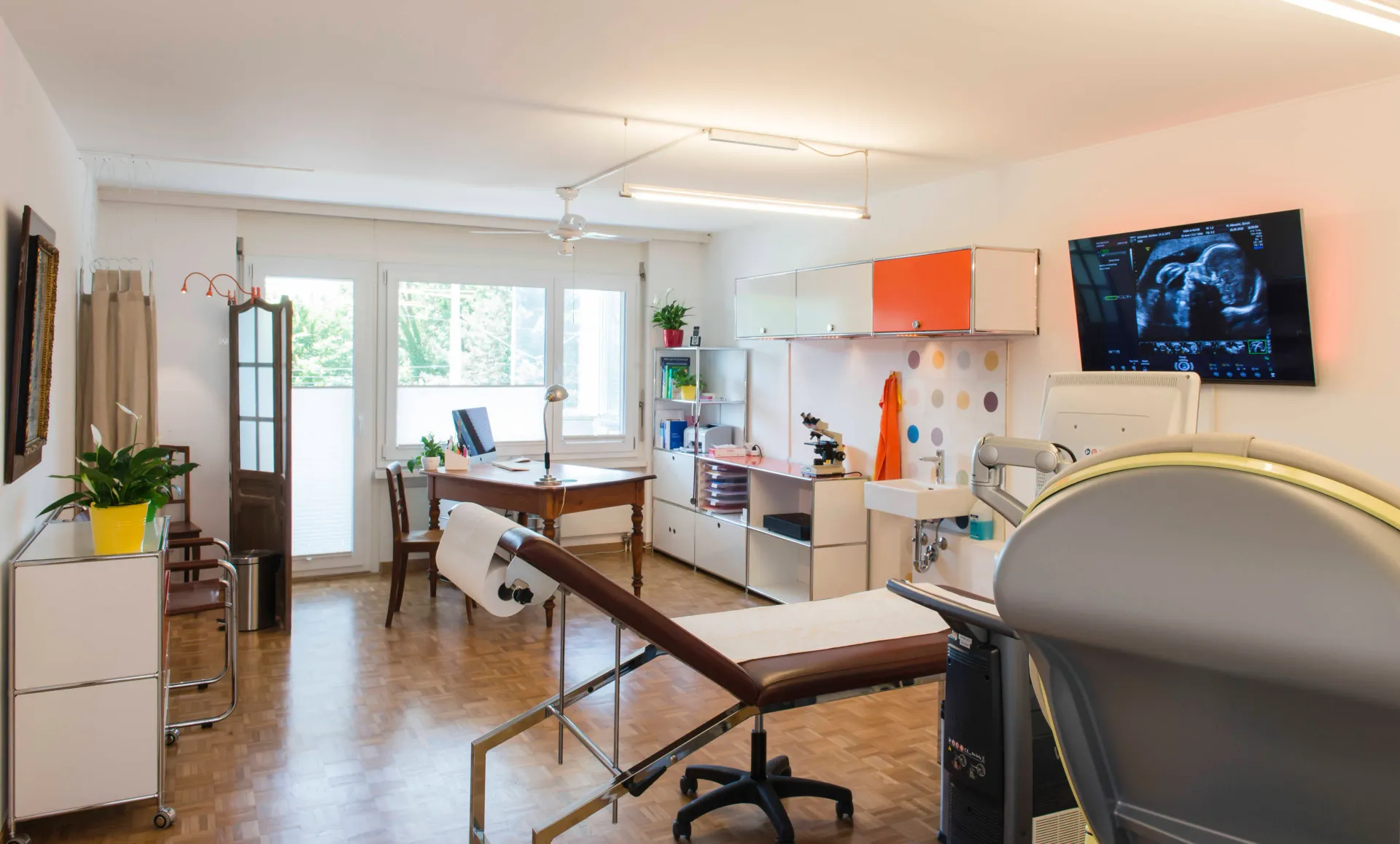 Bright, welcoming reception area of Frauenarztpraxis Höngg with orange accents and plants, conveying the warm, unhurried atmosphere described in the article.