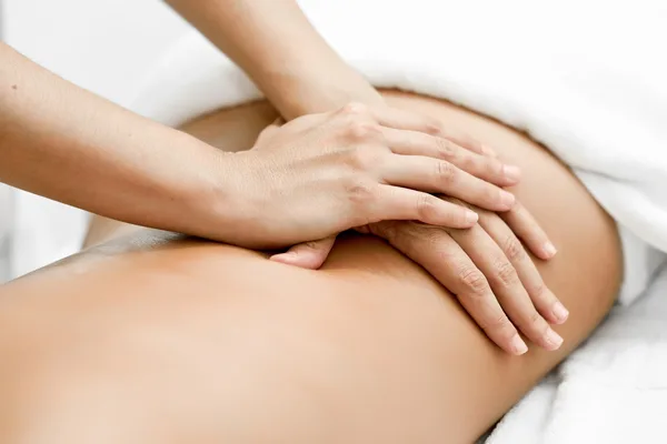 A therapist performs a professional back massage on a client lying on a treatment table.