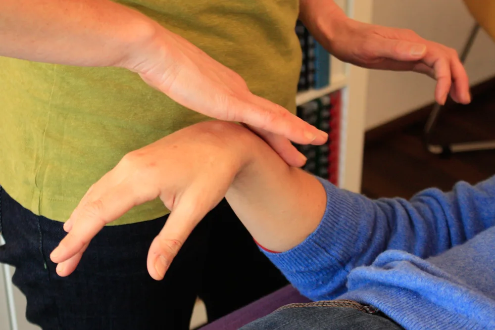 Therapist examines and manipulates a child's arm in a kinesiology assessment.