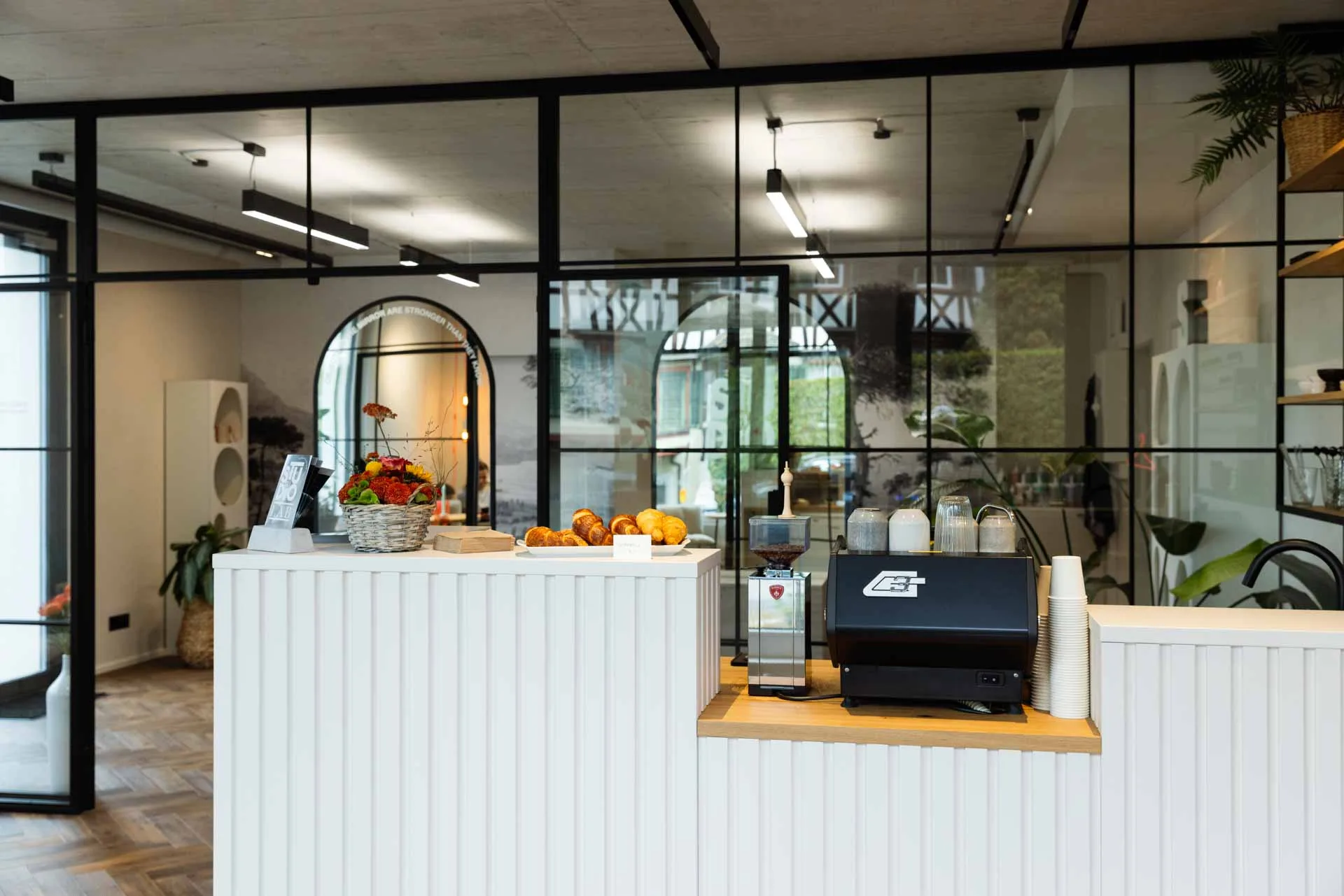 Open-plan studio interior with black-framed glass partitions and arched mirrors, showcasing the elegant, non-clinical design that sets this practice apart.
