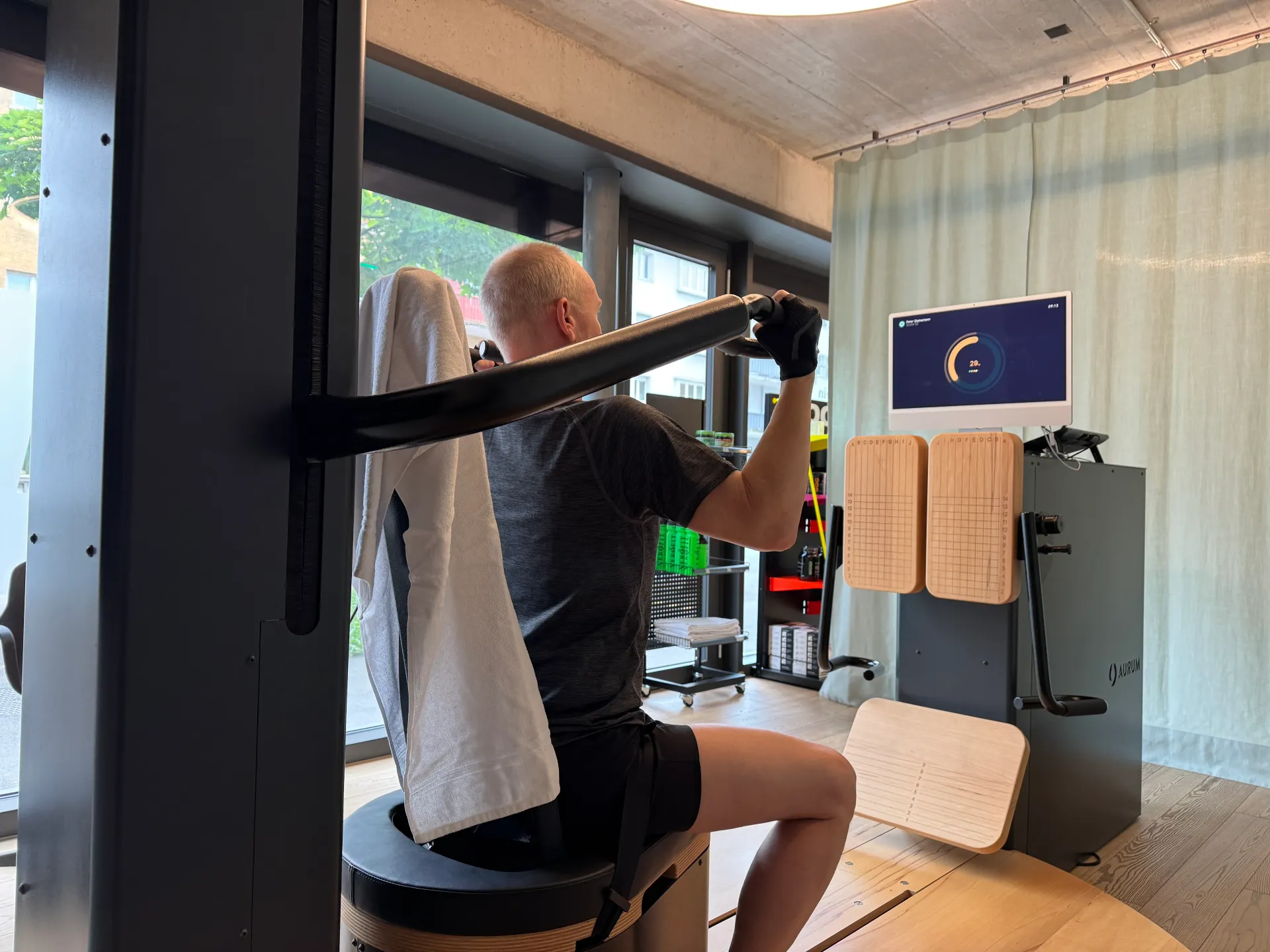 Personal trainer guiding client through targeted exercise on specialized equipment in well-lit studio setting.