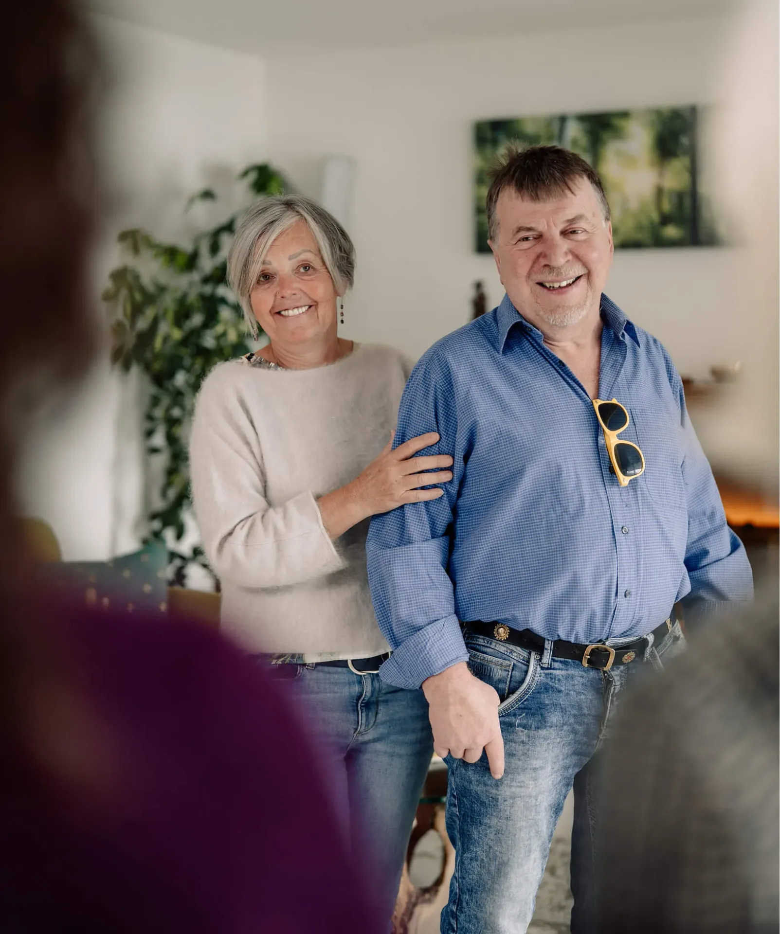 Woman and smiling man stand together warmly in a light-filled room.
