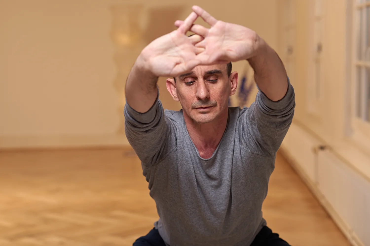 Marco Santi sits barefoot on a wooden chair in his studio, gazing calmly at the camera.