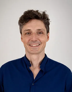 Portrait of Marek Bureš, a smiling male practitioner in a blue shirt against a neutral background.